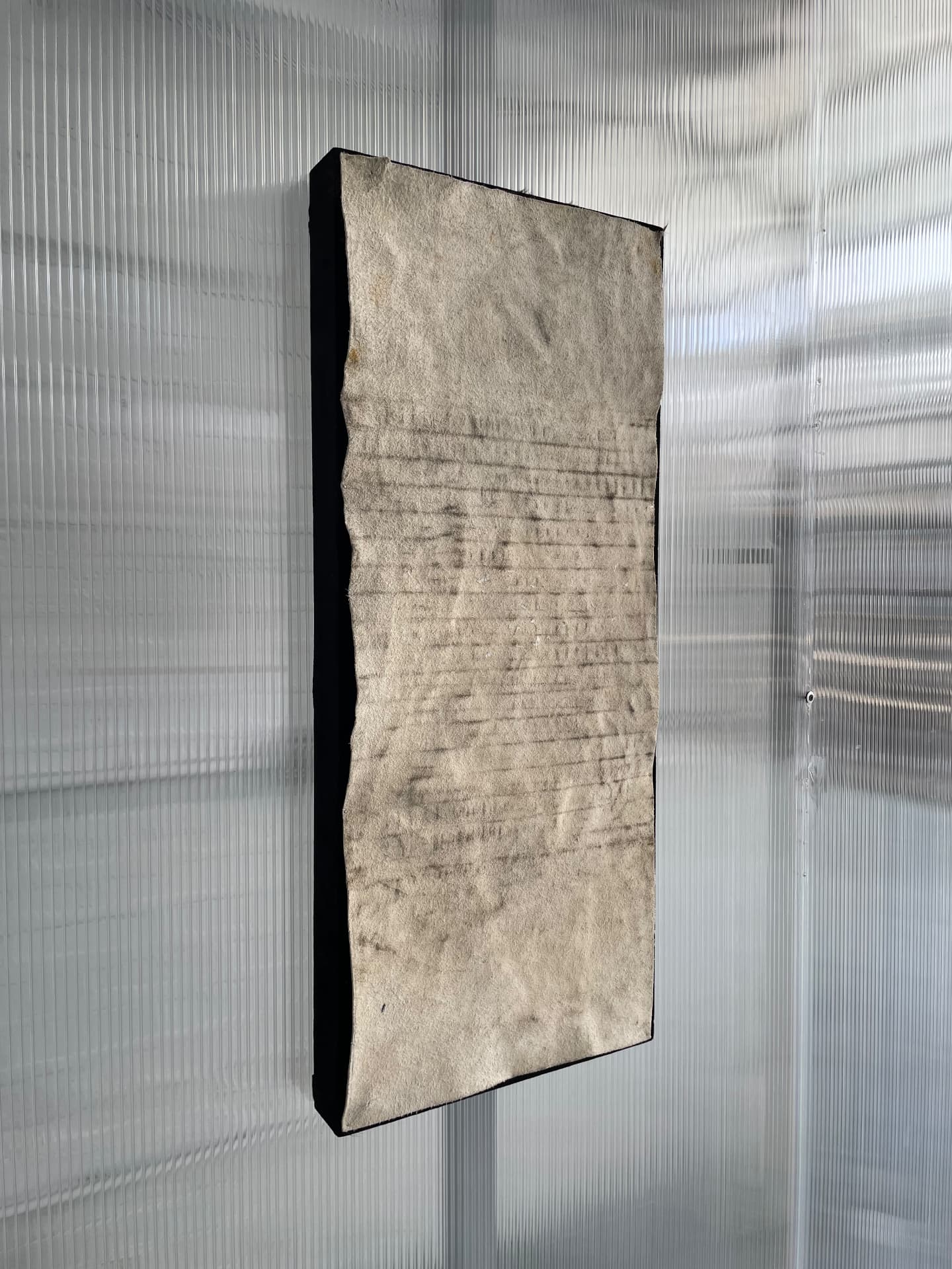 Pressed cowhide panel with grid imprints hanging against ribbed plastic