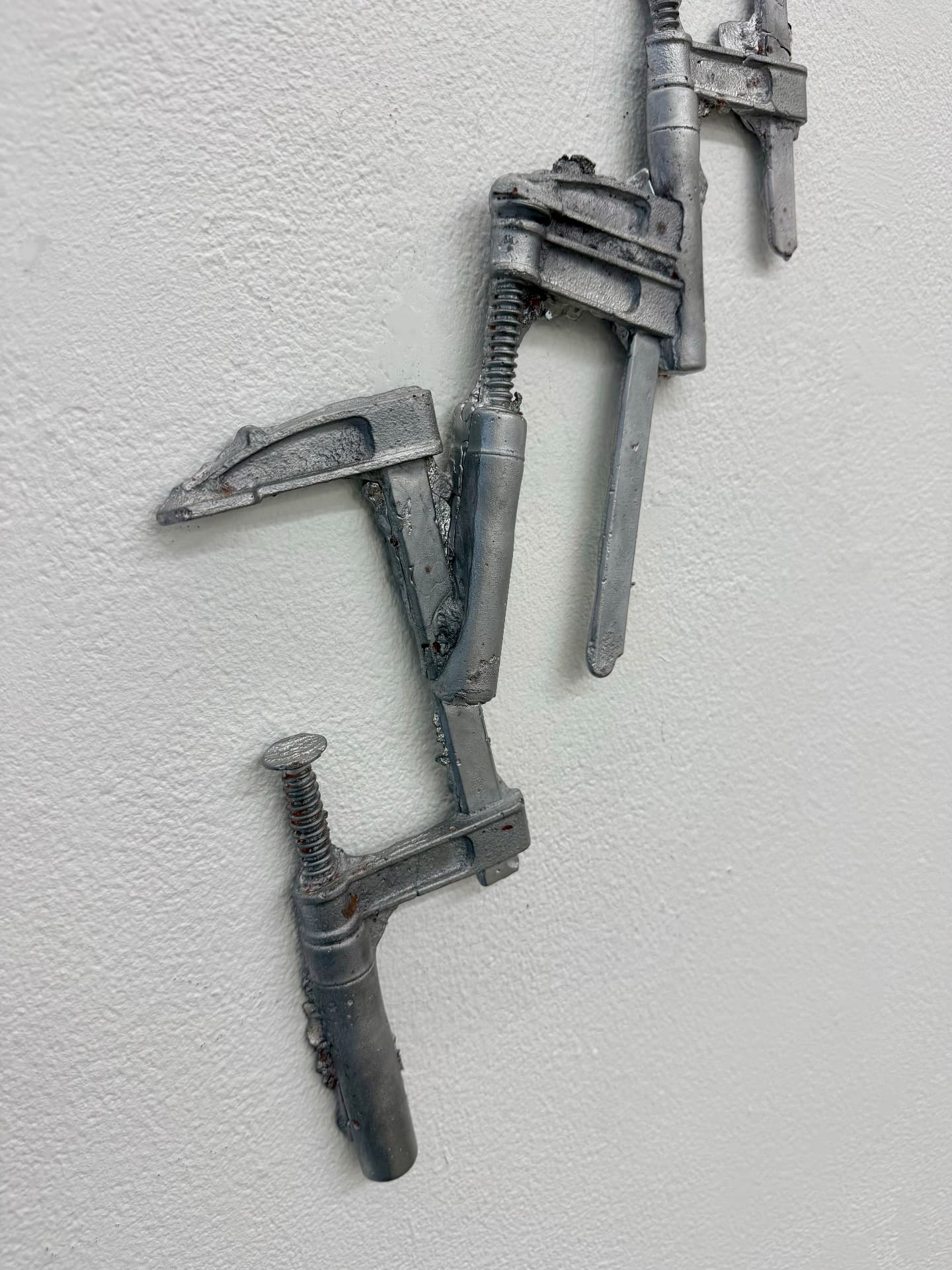 Detail of welded steel clamps mounted on a white wall