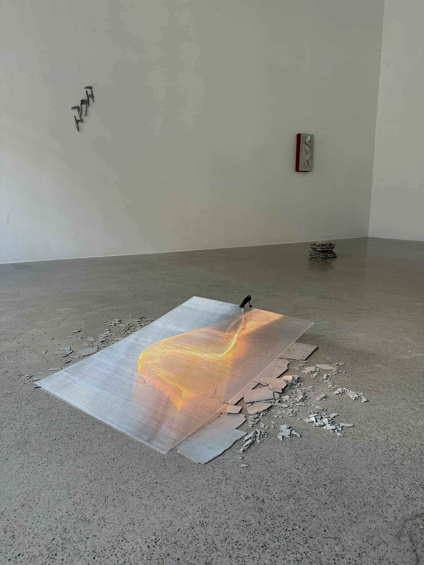 Wide installation view of the lit sheet with wall works in the background