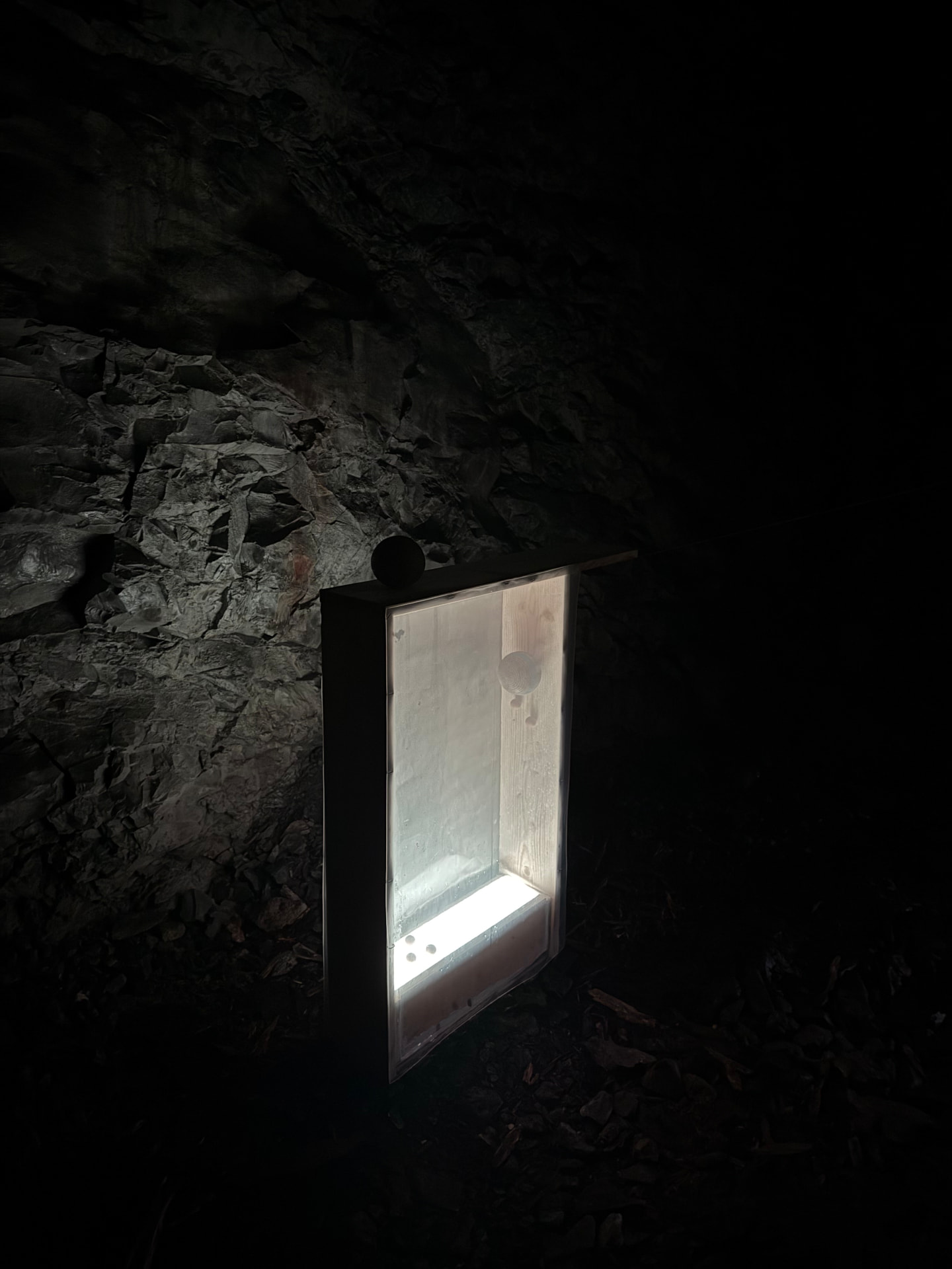 Illuminated wooden vitrine in the dark cave space