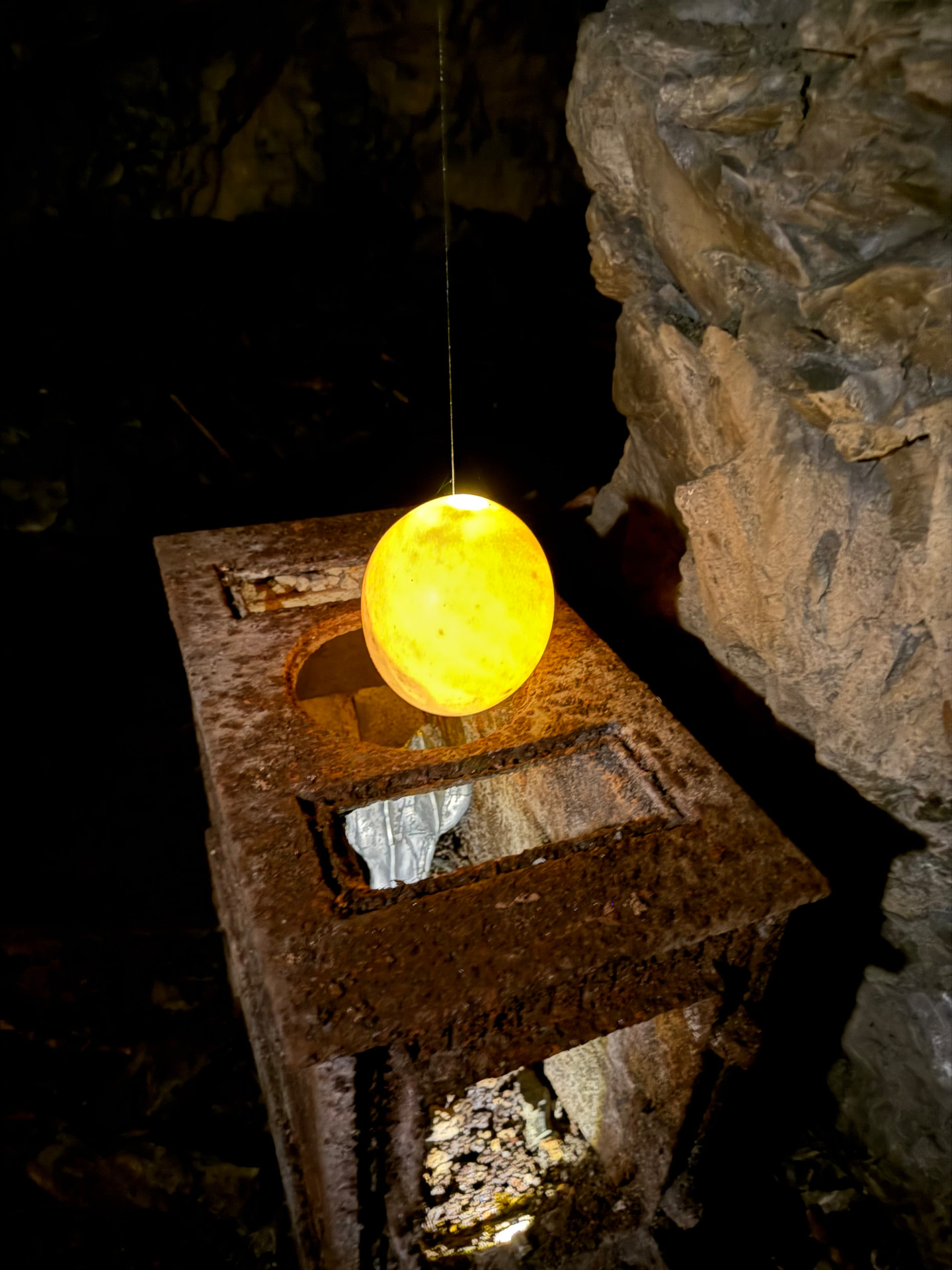 Glowing ostrich egg suspended above the rusted iron cabinet