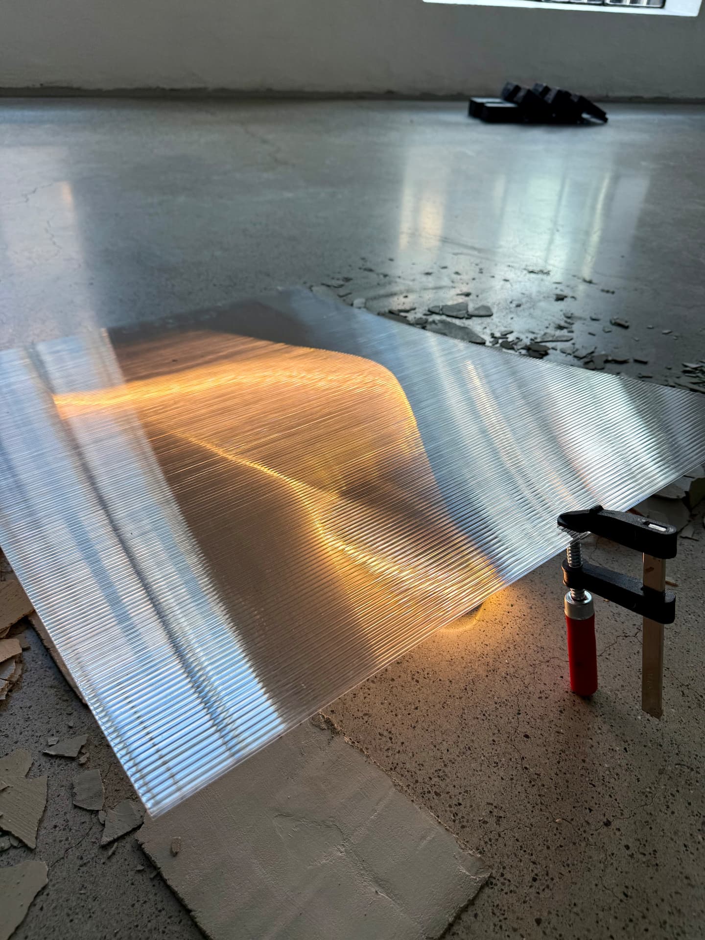 Polycarbonate sheet catching golden light in a white gallery space