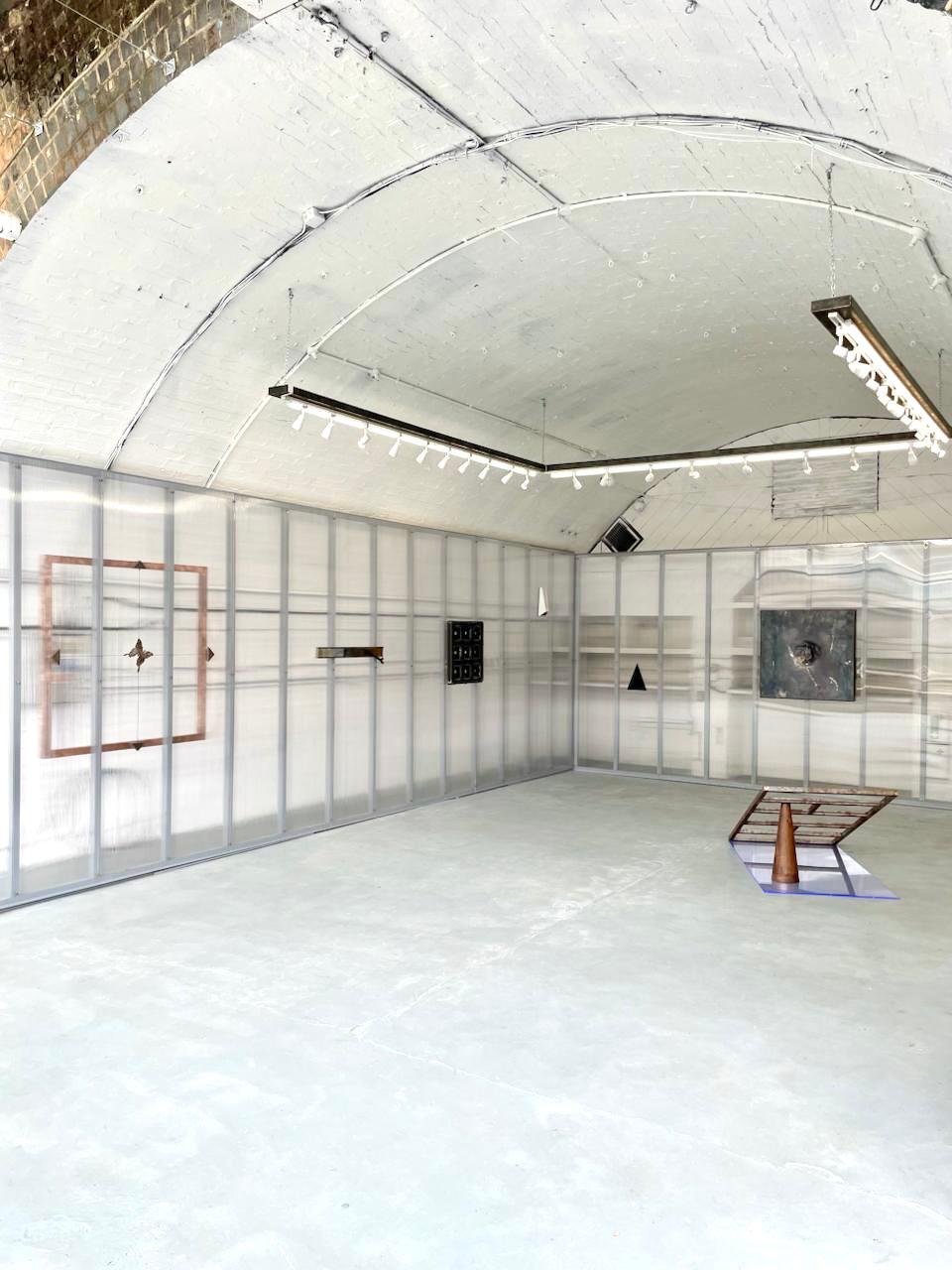 Wide view of the railway arch gallery with translucent polycarbonate walls and sculptural works