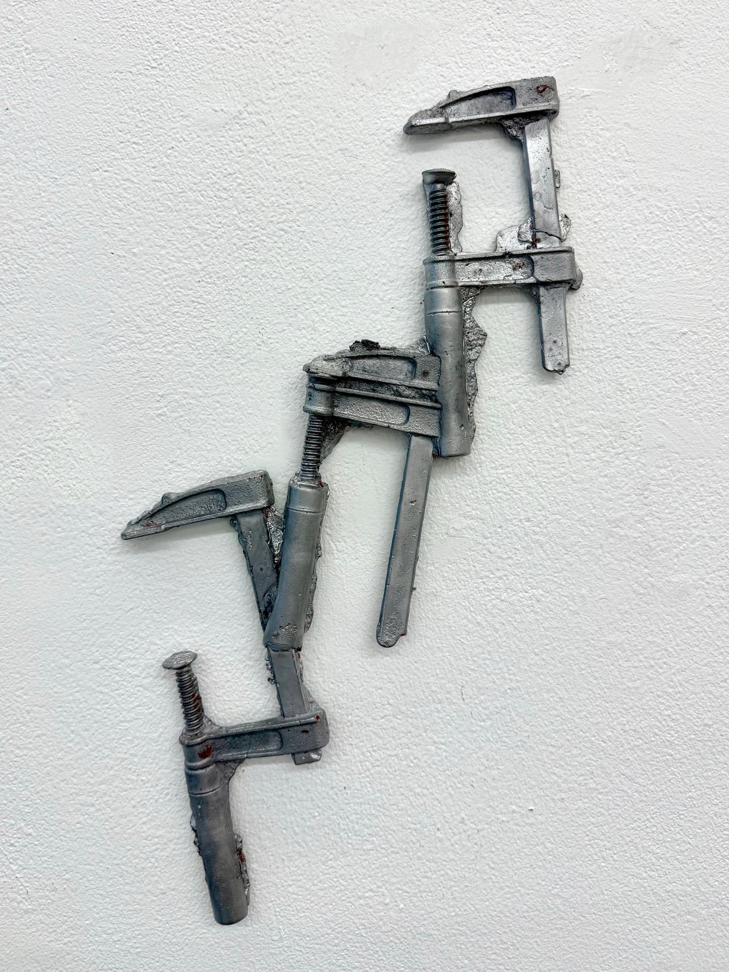 Welded steel clamps mounted on a white wall