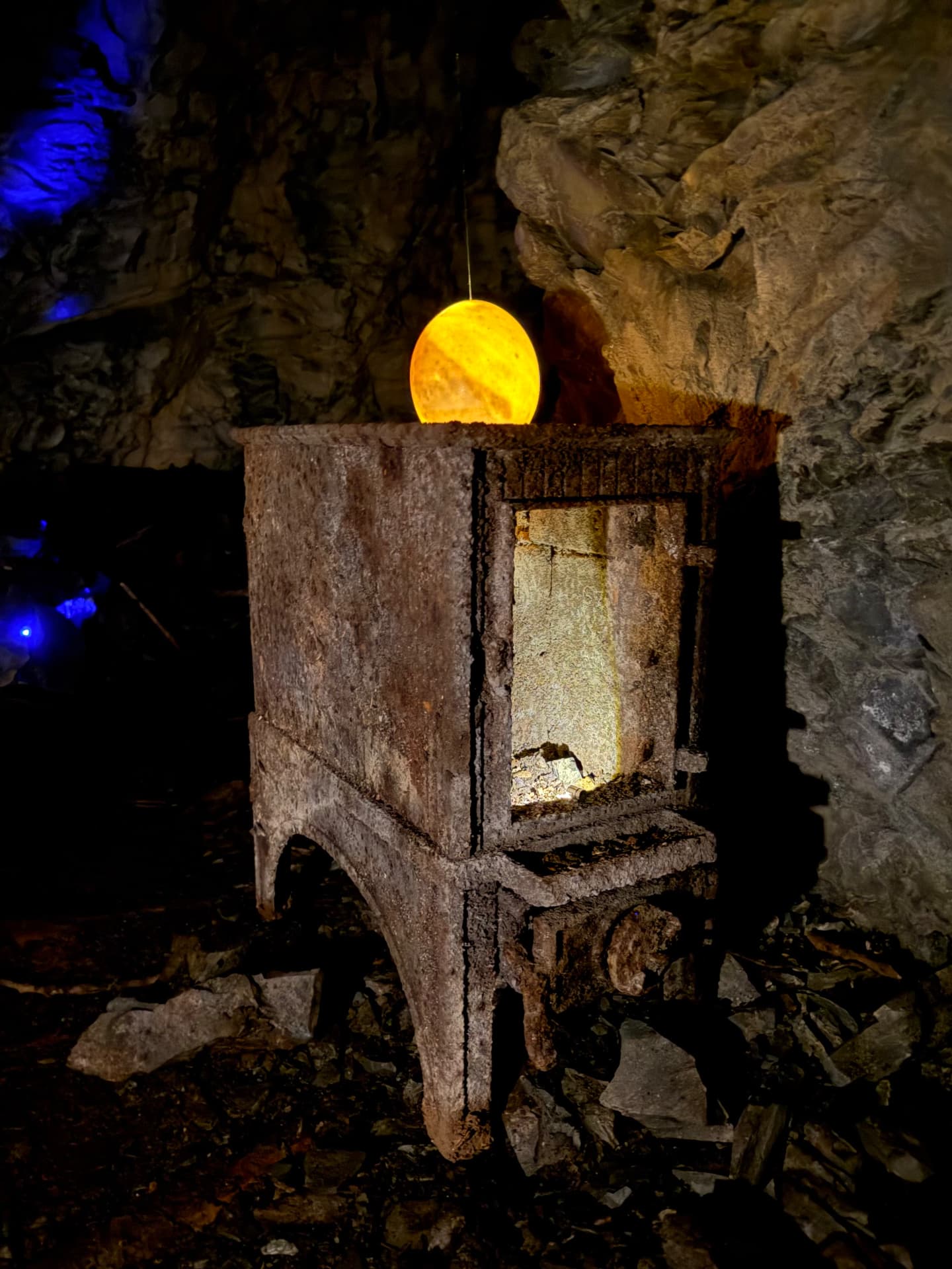 Rusted iron cabinet lit from within, a glowing orange orb resting on top